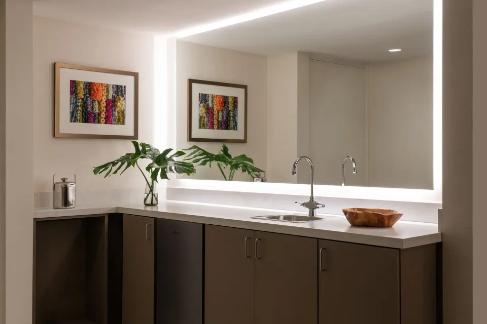 Renovated Corner Jr. Suite wet bar at Sheraton Princess Kaiulani with sink, cabinets, mirror, and artwork.
