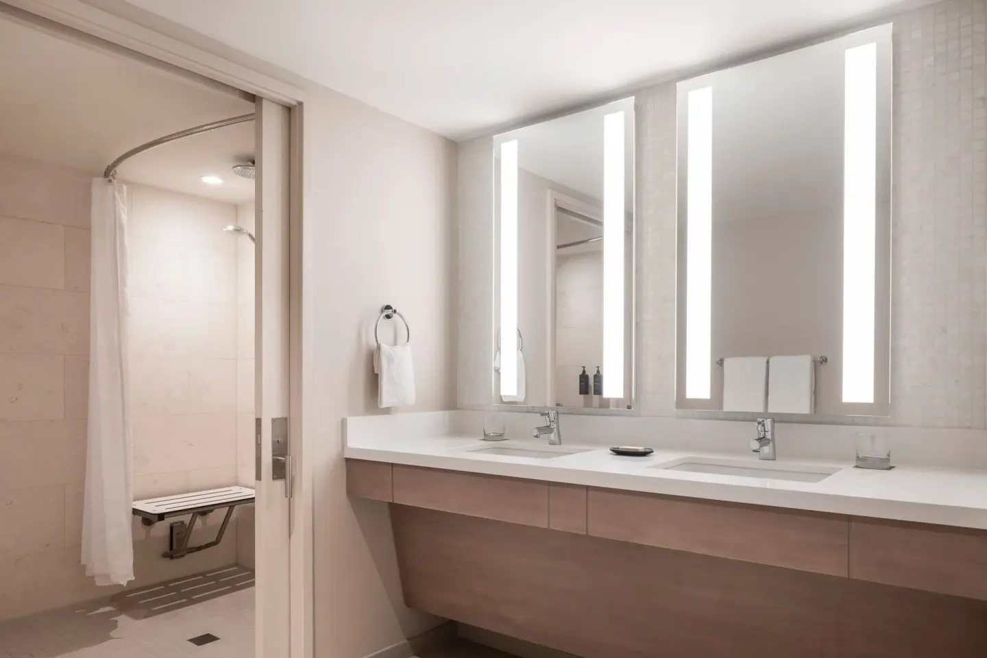 Accessible bathroom with double vanity, lit mirrors, and roll-in shower at Sheraton Waikiki Beach Resort.