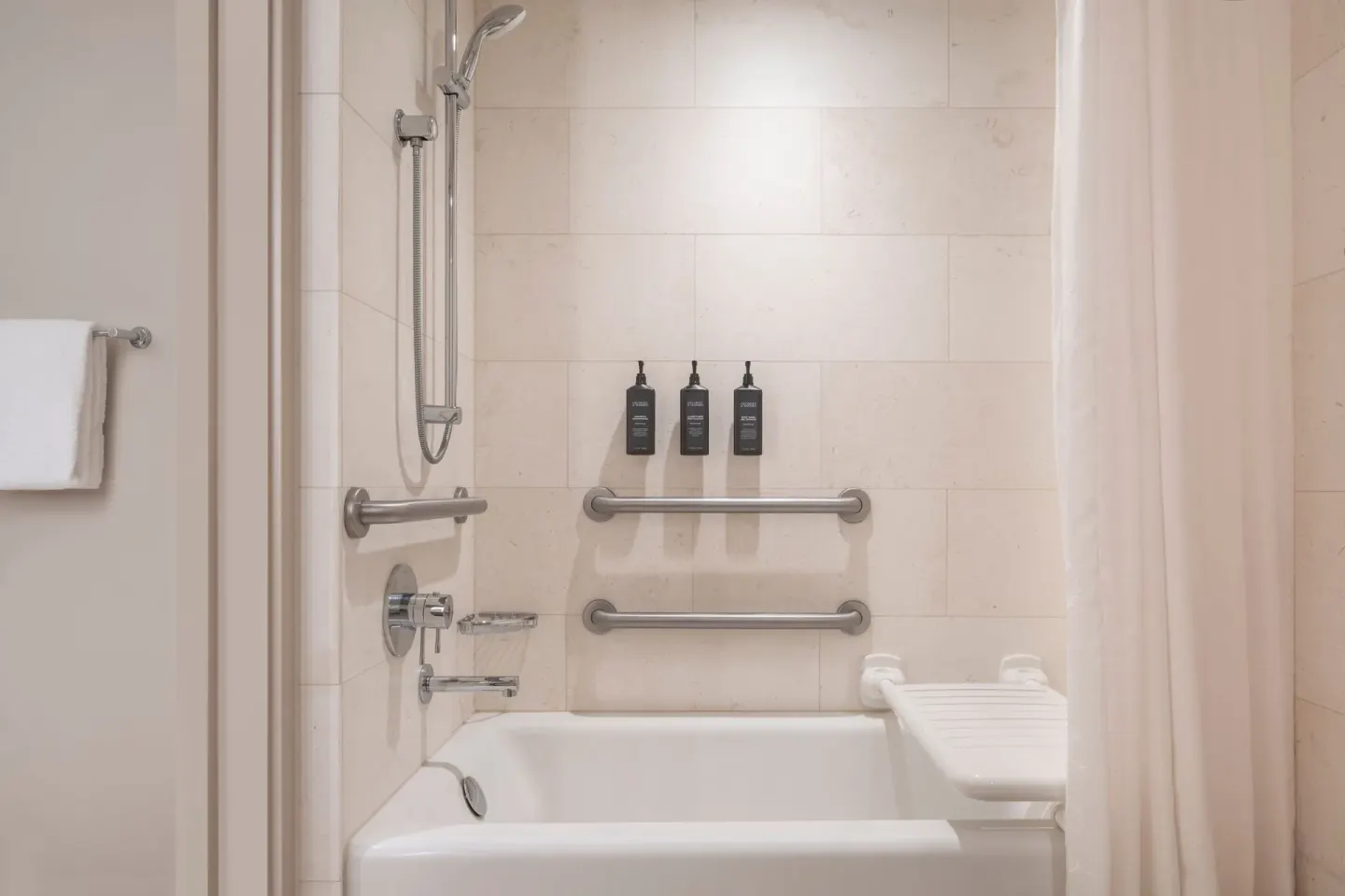 Accessible bathtub with grab bars, shower wand, curtain, and bath amenities at Sheraton Waikiki Beach Resort.