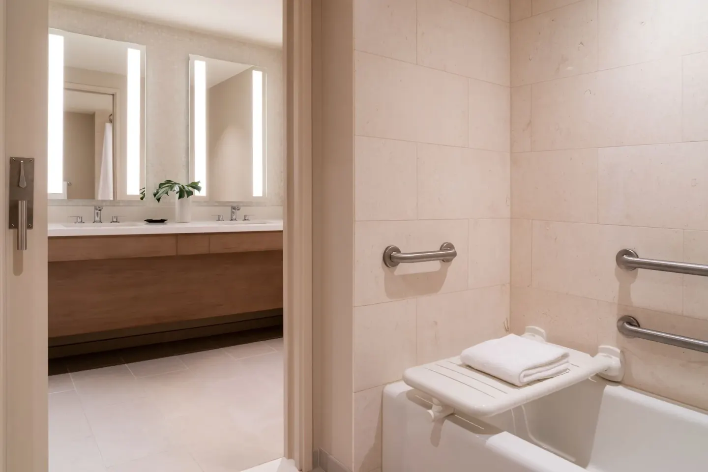 Accessible bathroom with grab bars, tub seat, and vanity beyond at Sheraton Waikiki Beach Resort.
