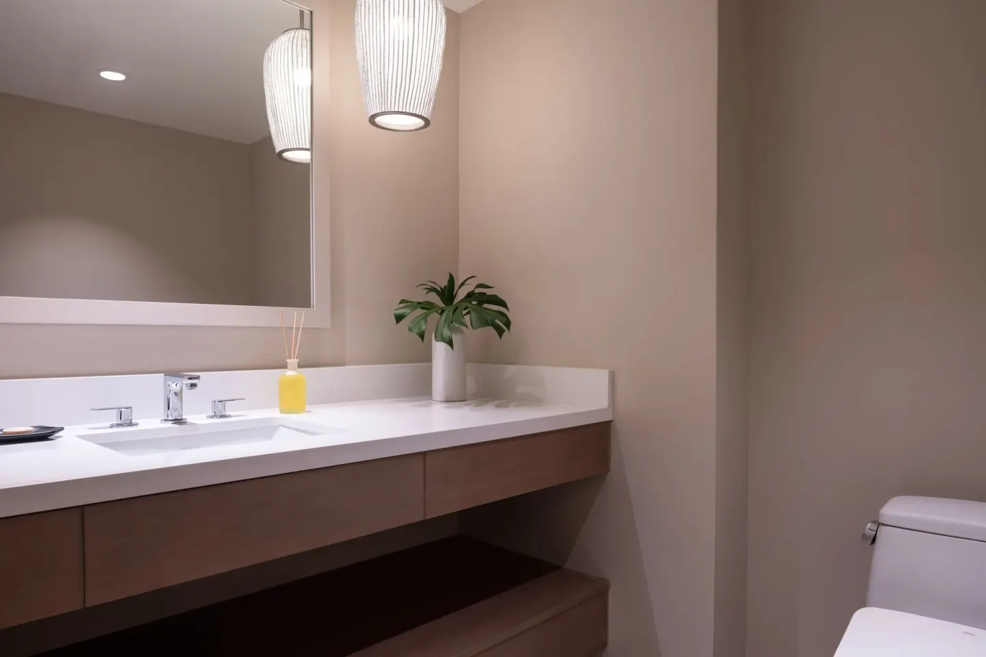 Bathroom vanity with vessel-style sink, mirror, pendant light, and toilet at Sheraton Waikiki Beach Resort.