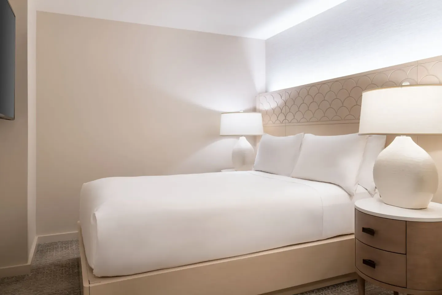 White king bed with bedside lamps in a guest room at Sheraton Waikiki Beach Resort.