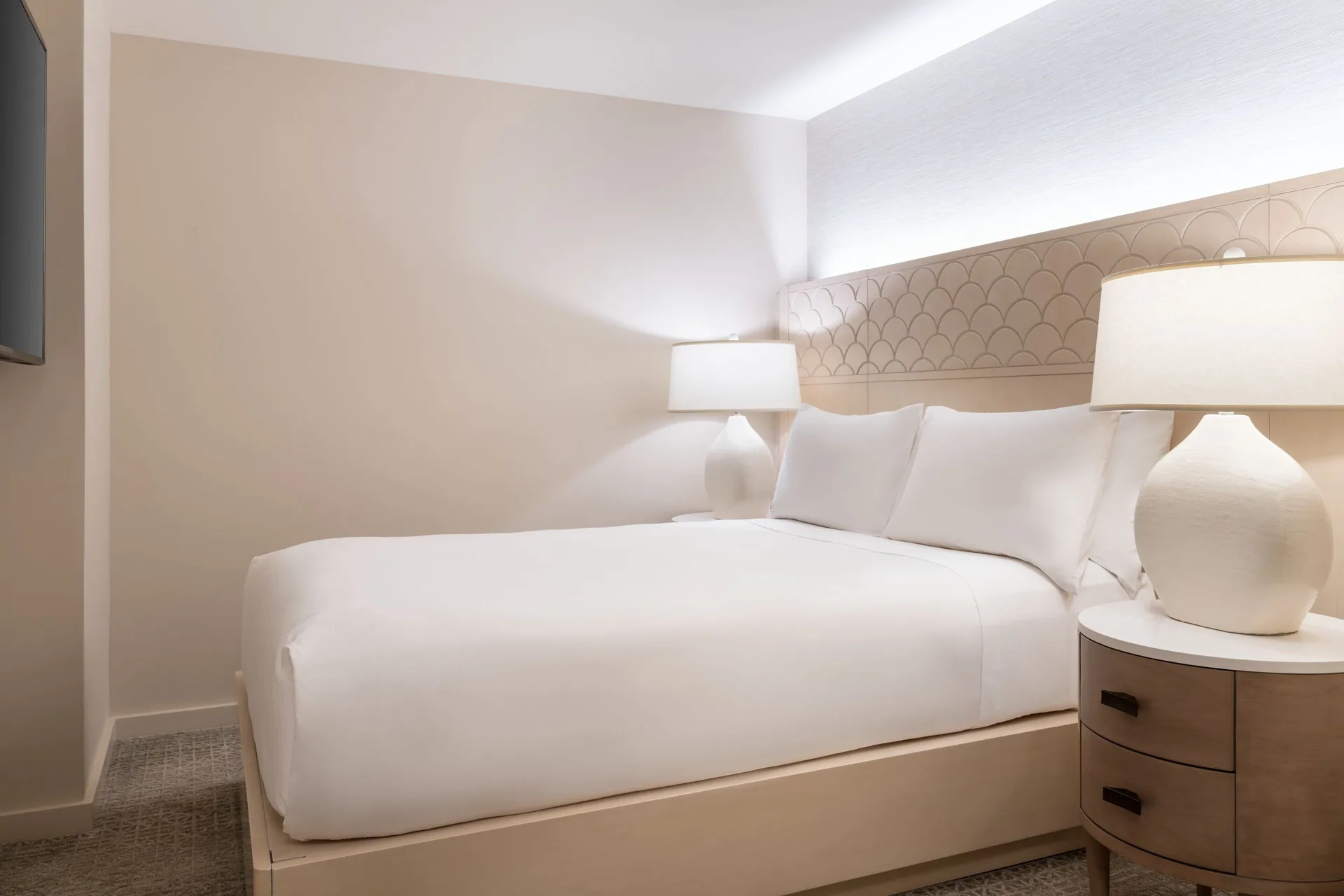 White king bed with bedside lamps in a guest room at Sheraton Waikiki Beach Resort.
