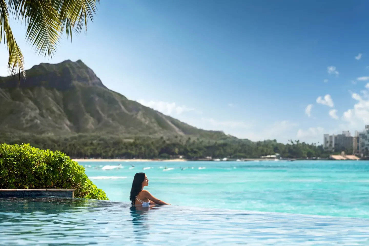 Guest in an infinity pool overlooking Diamond Head at Sheraton Waikiki Beach Resort.