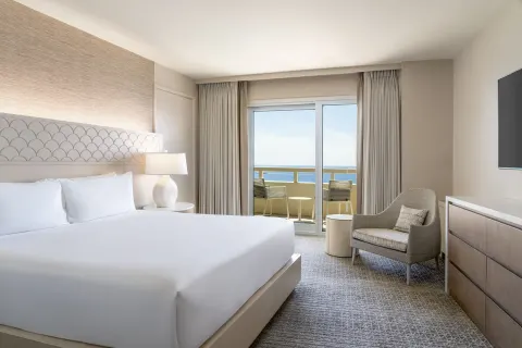 King-bed guest room with ocean-facing balcony at Sheraton Waikiki Beach Resort.