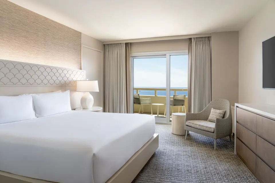 King-bed guest room with ocean-facing balcony at Sheraton Waikiki Beach Resort.