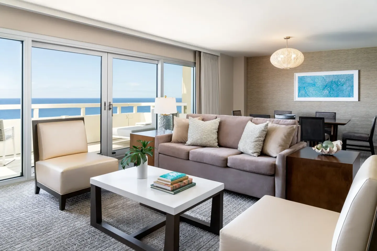 Suite living room with balcony, sofa, and dining table at Sheraton Waikiki Beach Resort.
