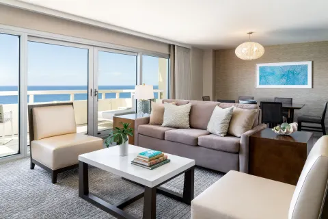 Suite living room with balcony, sofa, and dining table at Sheraton Waikiki Beach Resort.