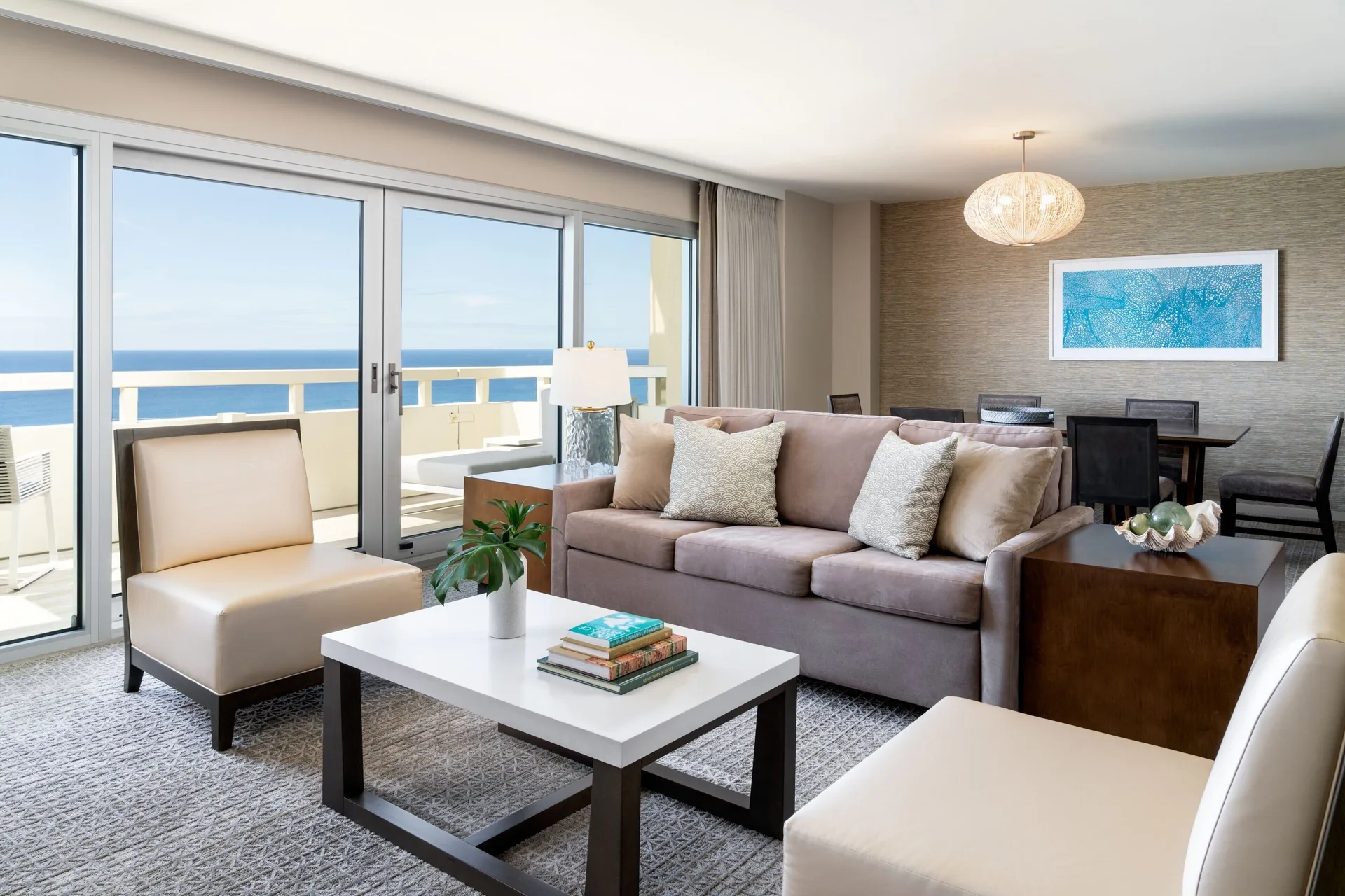 Suite living room with balcony, sofa, and dining table at Sheraton Waikiki Beach Resort.
