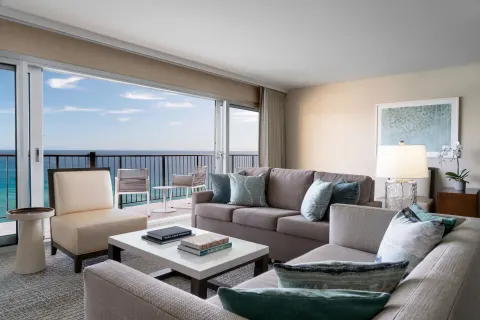 Living room with sofas and oceanfront balcony at Sheraton Waikiki Beach Resort.