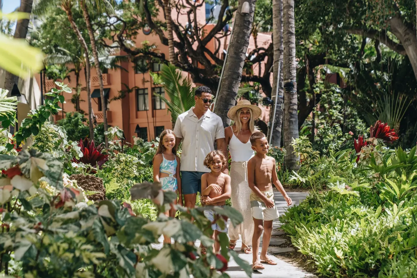Family walking through tropical gardens at Sheraton Waikiki Beach Resort.