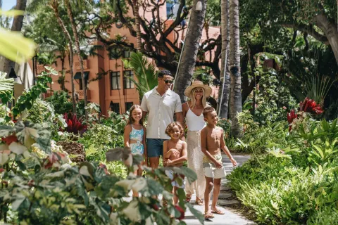 Family walking through tropical gardens at Sheraton Waikiki Beach Resort.
