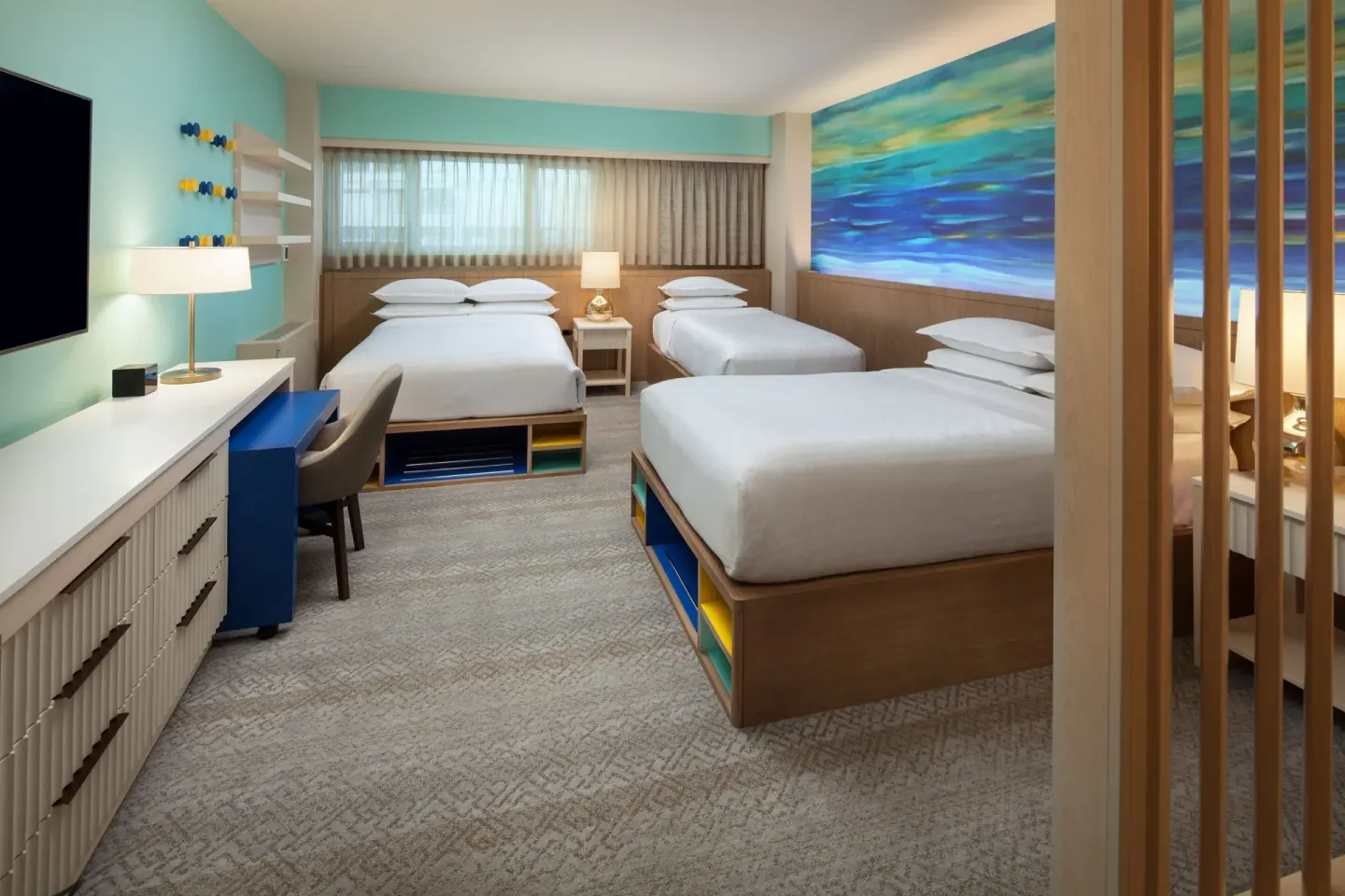 Family room with multiple beds, desk, and window at Sheraton Waikiki Beach Resort.