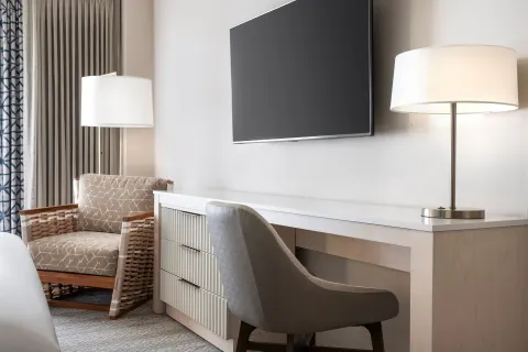 City View room desk, TV, lamps, and armchair at Sheraton Waikiki Beach Resort.