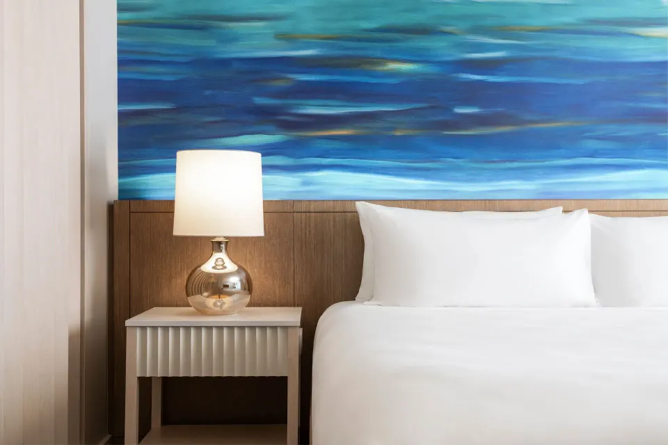 King bed detail with blue wall art in a City View room at Sheraton Waikiki Beach Resort.