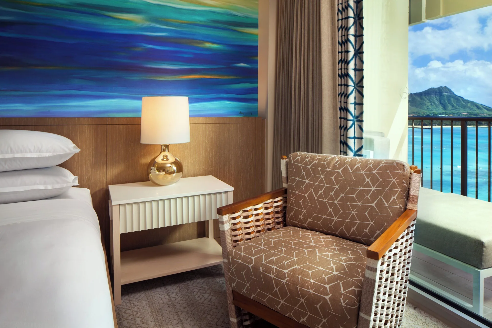 Guest room chair beside the bed and balcony view at Sheraton Waikiki Beach Resort.