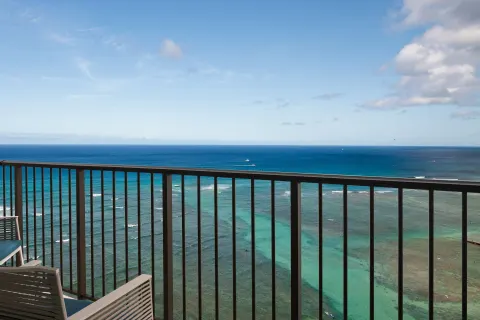 Oceanfront balcony with chairs overlooking the Pacific at Sheraton Waikiki Beach Resort.
