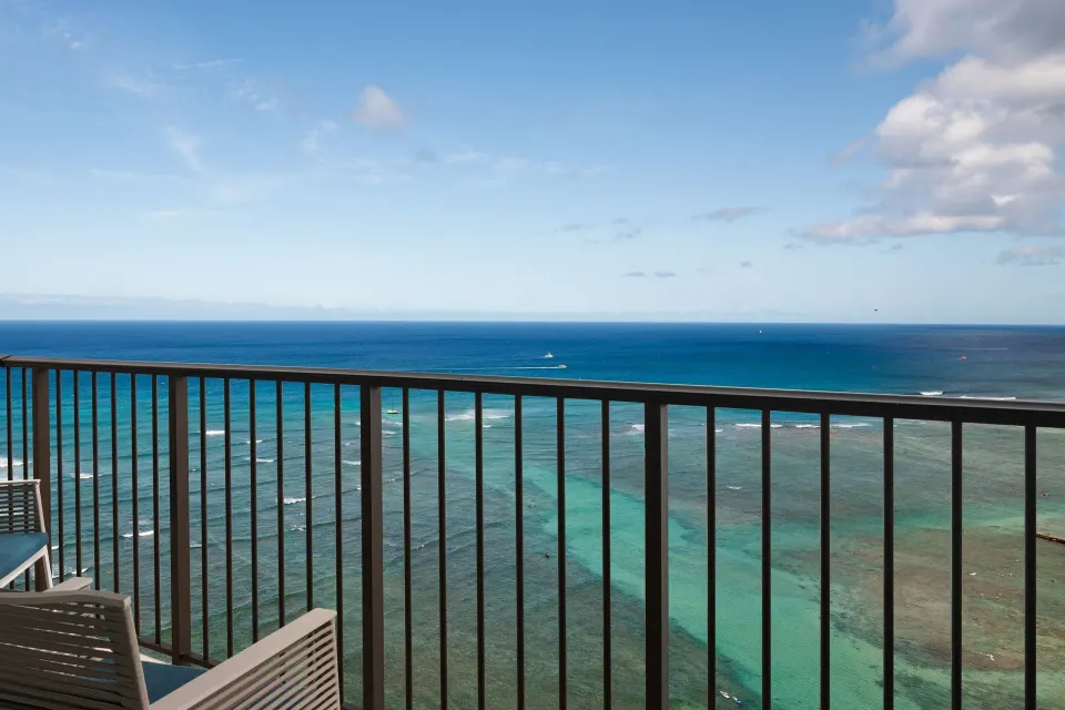 Oceanfront balcony with chairs overlooking the Pacific at Sheraton Waikiki Beach Resort.