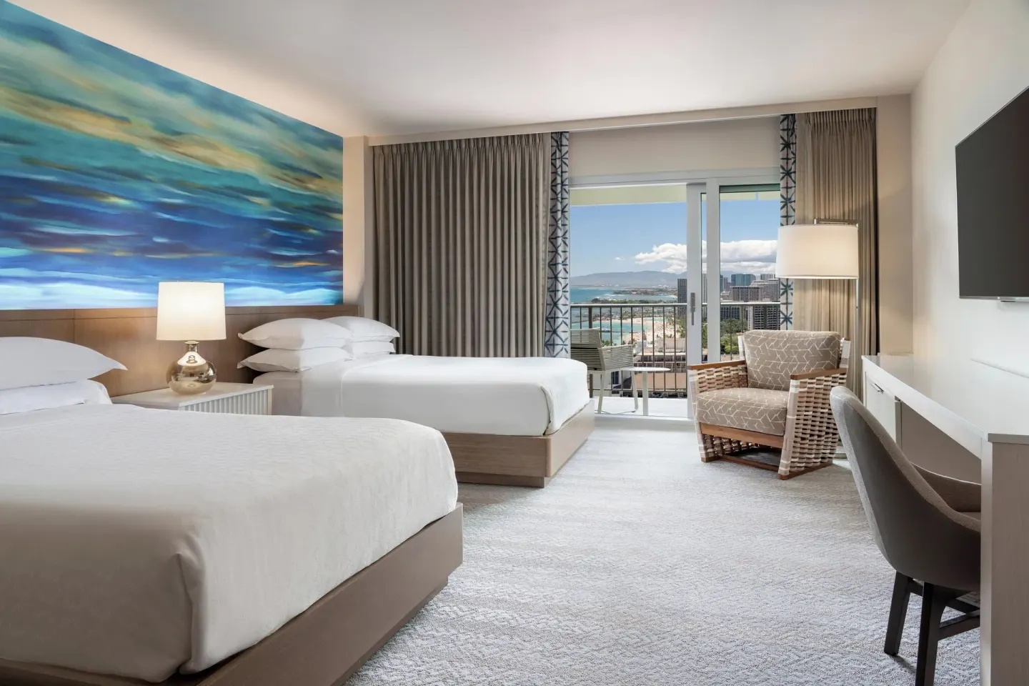 Two-bed guest room with balcony and partial ocean view at Sheraton Waikiki Beach Resort.