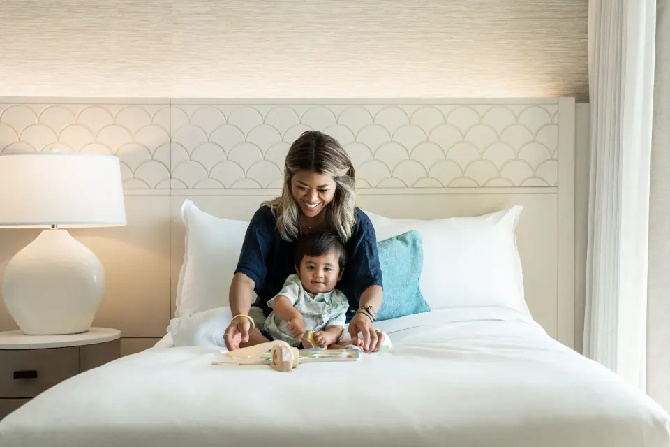 King bed with family seated against a patterned headboard at Sheraton Waikiki Beach Resort.