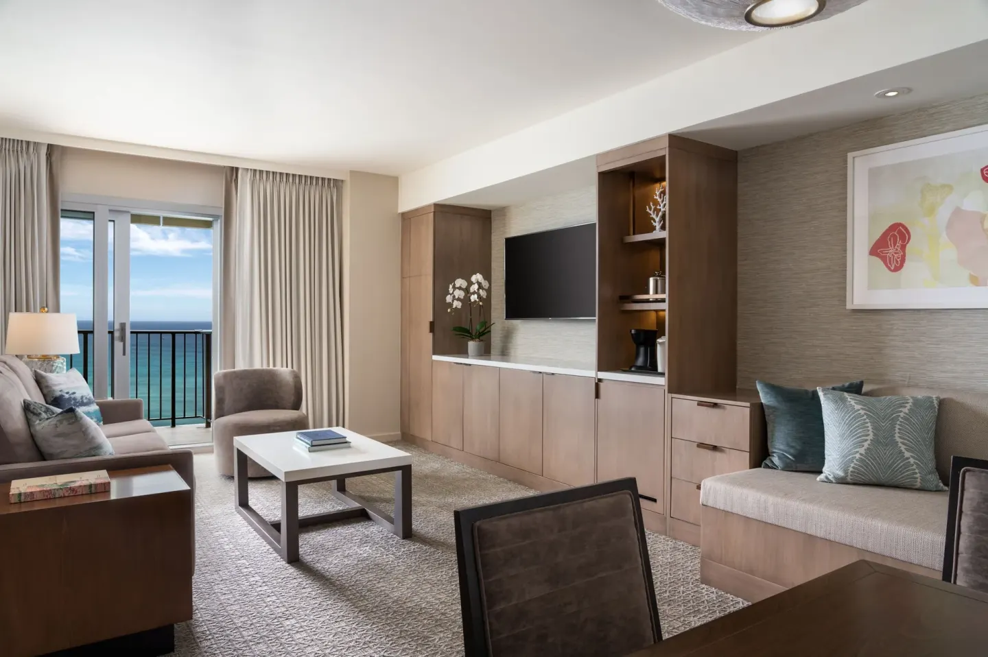 Living and dining area with balcony ocean view at Sheraton Waikiki Beach Resort.