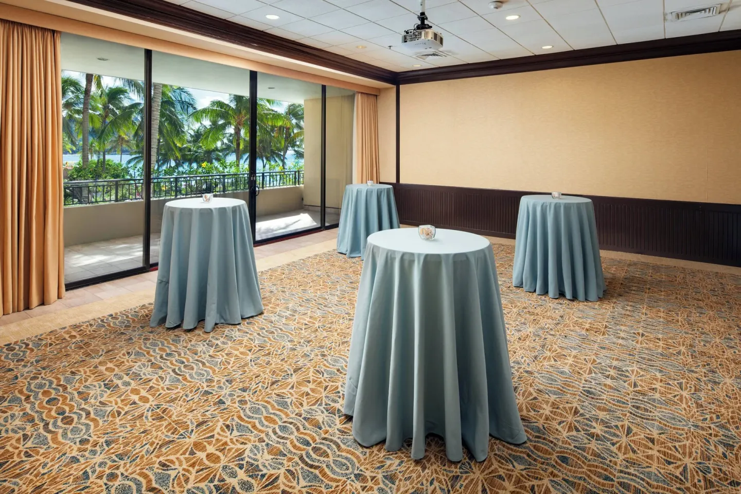 Event room at Sheraton Waikiki Beach Resort with cocktail tables and balcony views of palms.