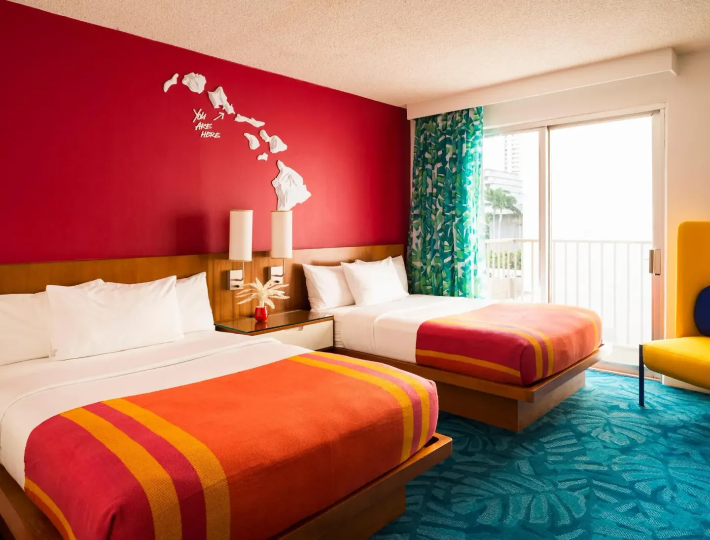 Colorful two-bed guest room with balcony doors at Shoreline Hotel Waikiki.