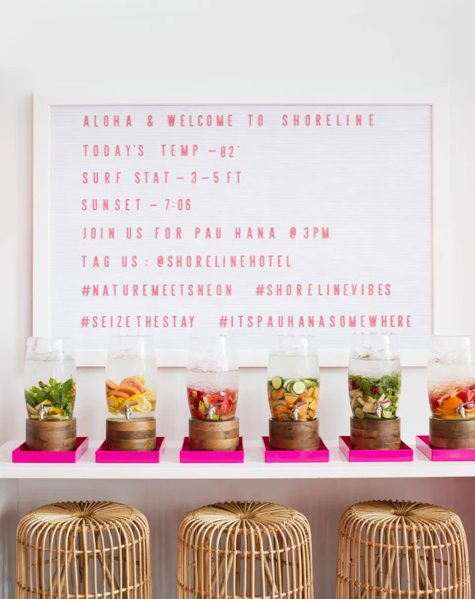 Welcome letter board and fruit-infused drink dispensers at Shoreline Hotel Waikiki.