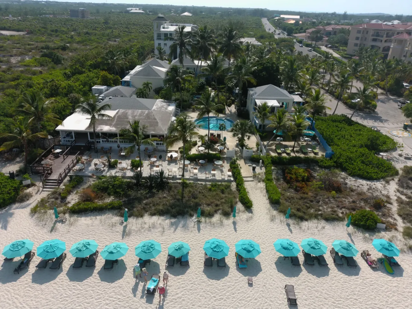 Aerial view of Sibonné Beach Hotel, pool, patio, and beach umbrellas.