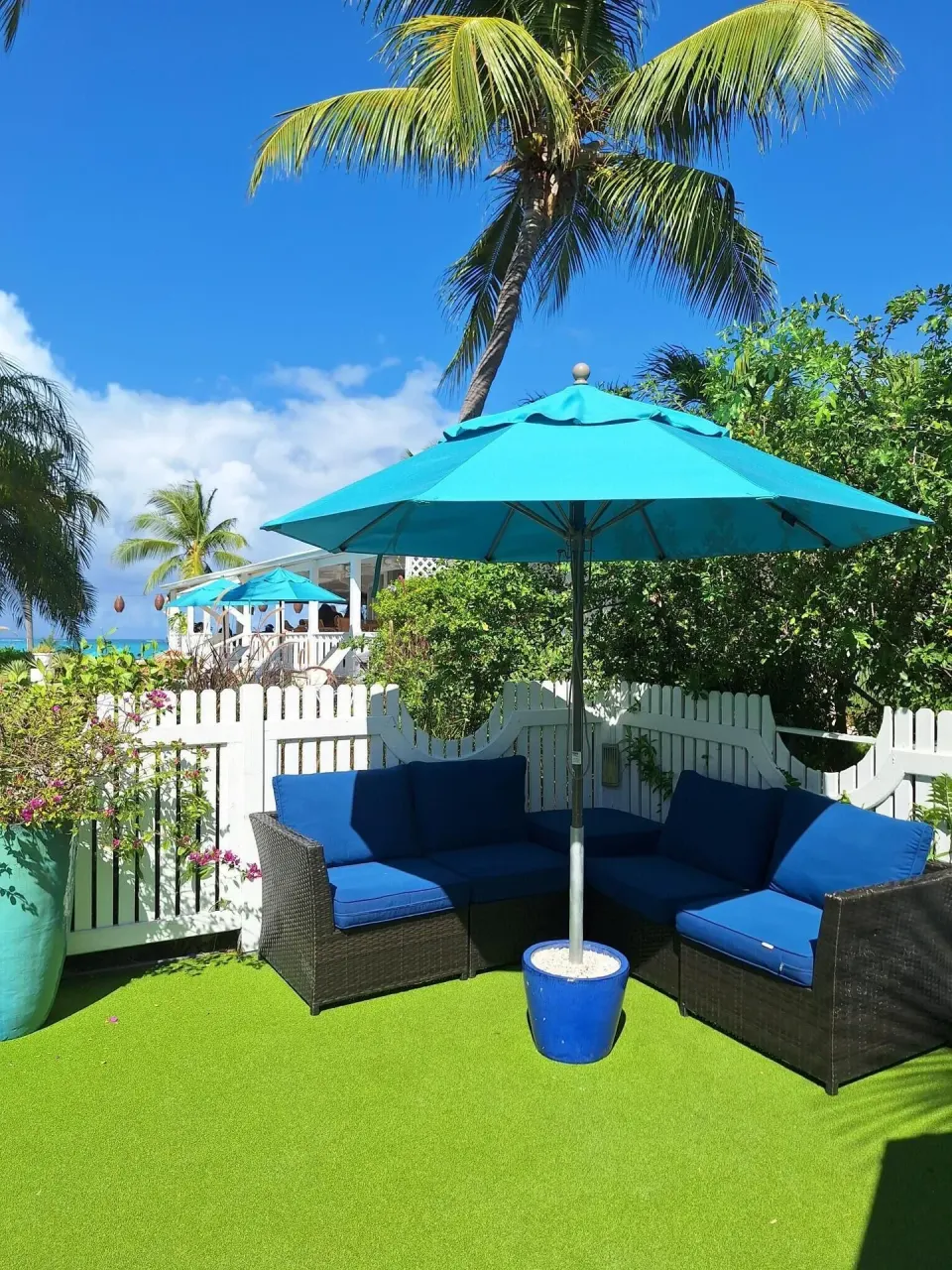 Outdoor sofa seating under a turquoise umbrella at Sibonné Beach Hotel.