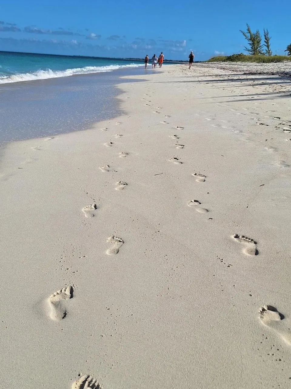 Footprints in white sand along the shoreline near Sibonné Beach Hotel.