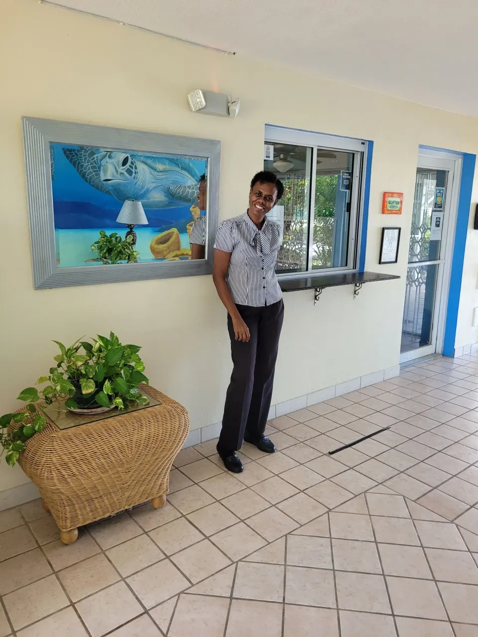 A staff member stands by the front desk and turtle artwork at Sibonné Beach Hotel.