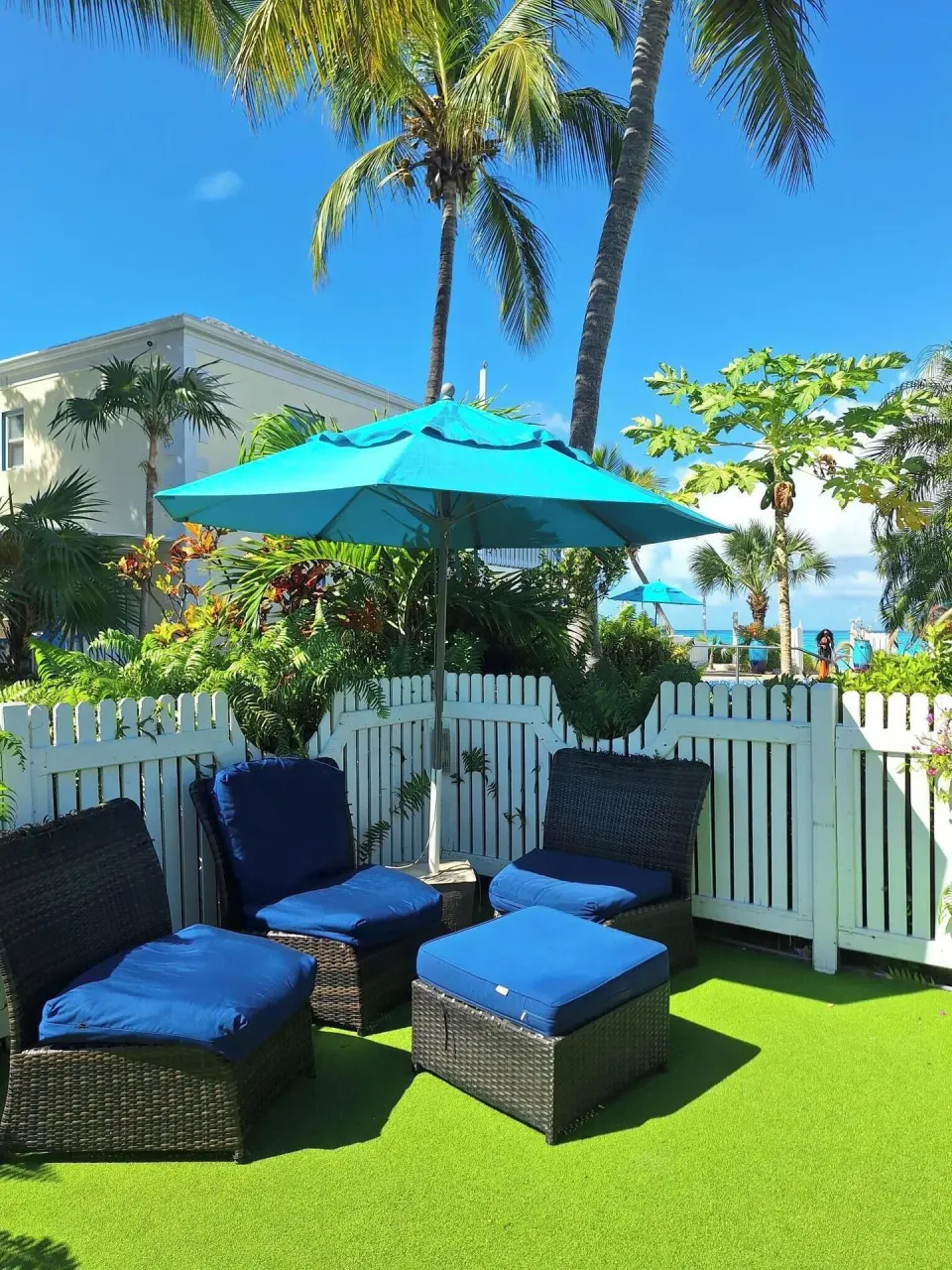 Blue-cushioned patio seating under a turquoise umbrella at Sibonné Beach Hotel.