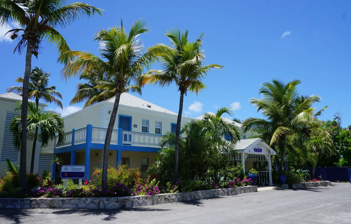 Palm-lined entrance and pastel buildings at Sibonné Beach Hotel.