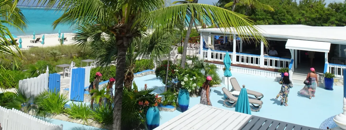 Pool deck and beachside building framed by palms at Sibonné Beach Hotel.