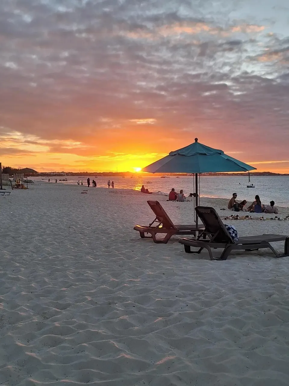 Sunset over the beach with lounge chairs and an umbrella at Sibonné Beach Hotel.