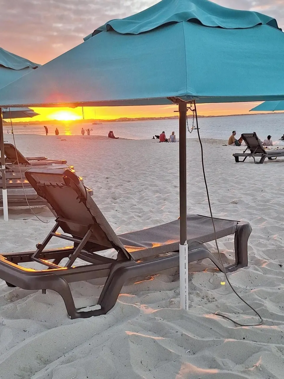 Sunset over beach loungers and turquoise umbrellas at Sibonné Beach Hotel.