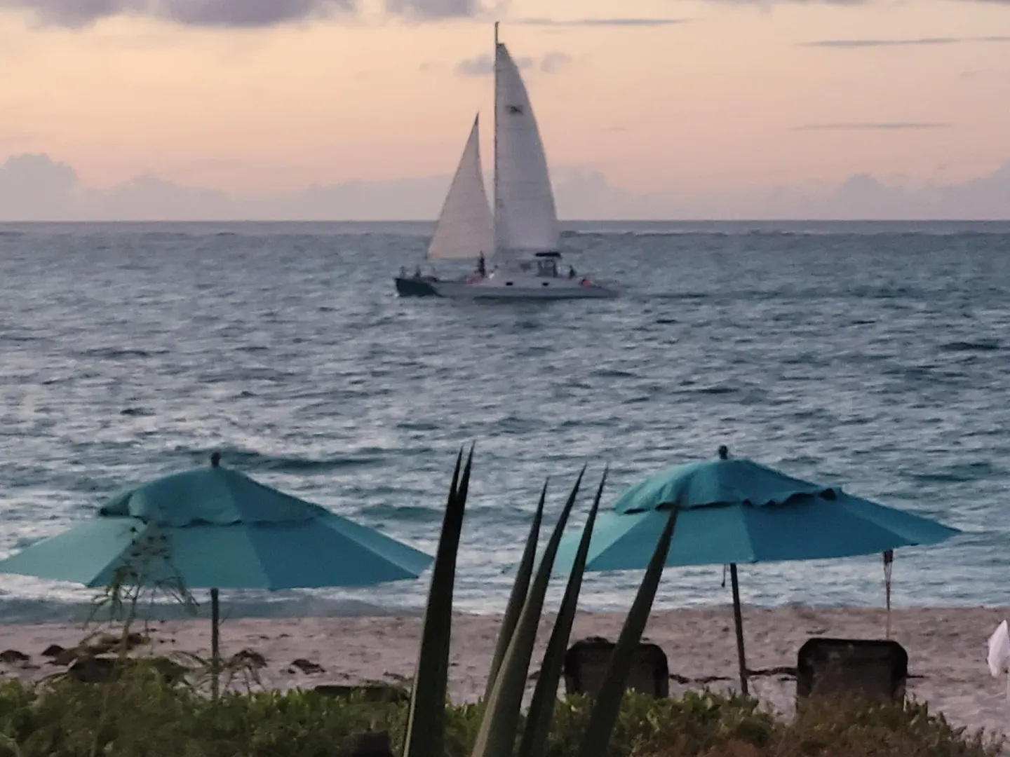 Sailboat offshore beyond beach umbrellas at Sibonné Beach Hotel.