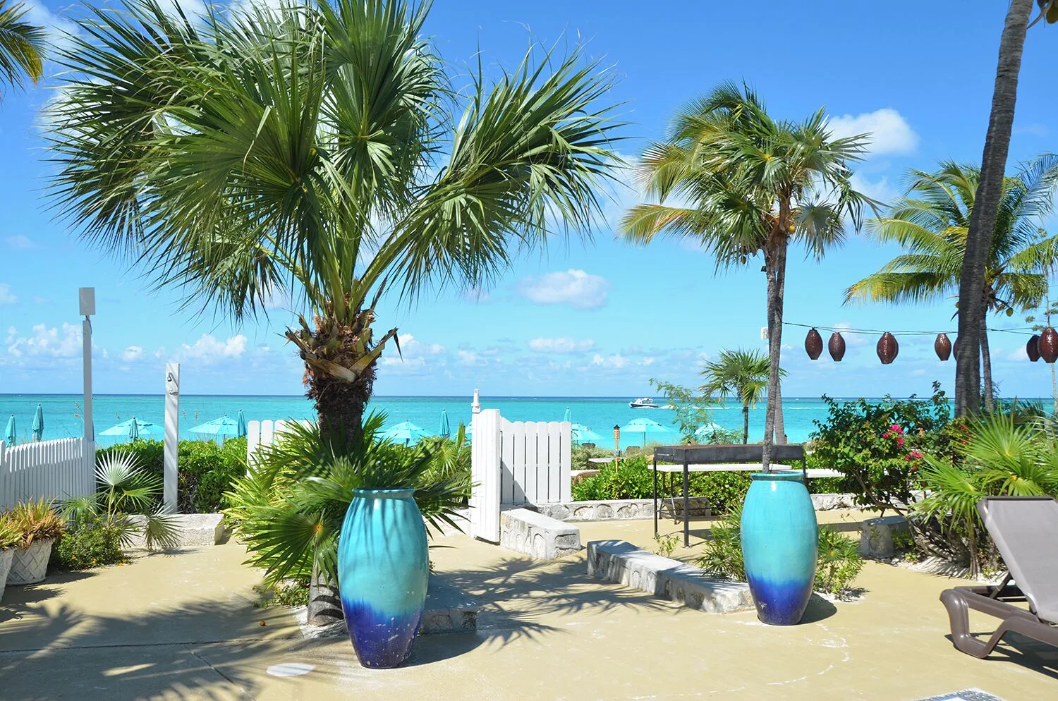 Tropical courtyard with palms, blue vases, and beach beyond at Sibonné Beach Hotel.