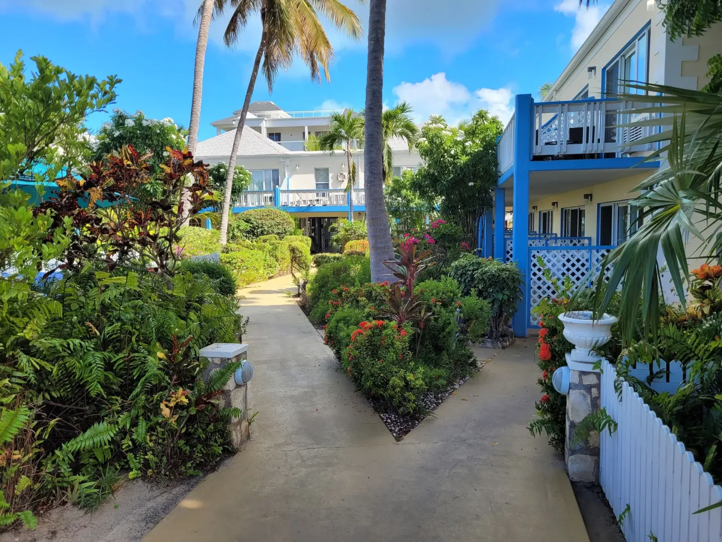 Garden walkway between blue-trimmed buildings at Sibonné Beach Hotel.