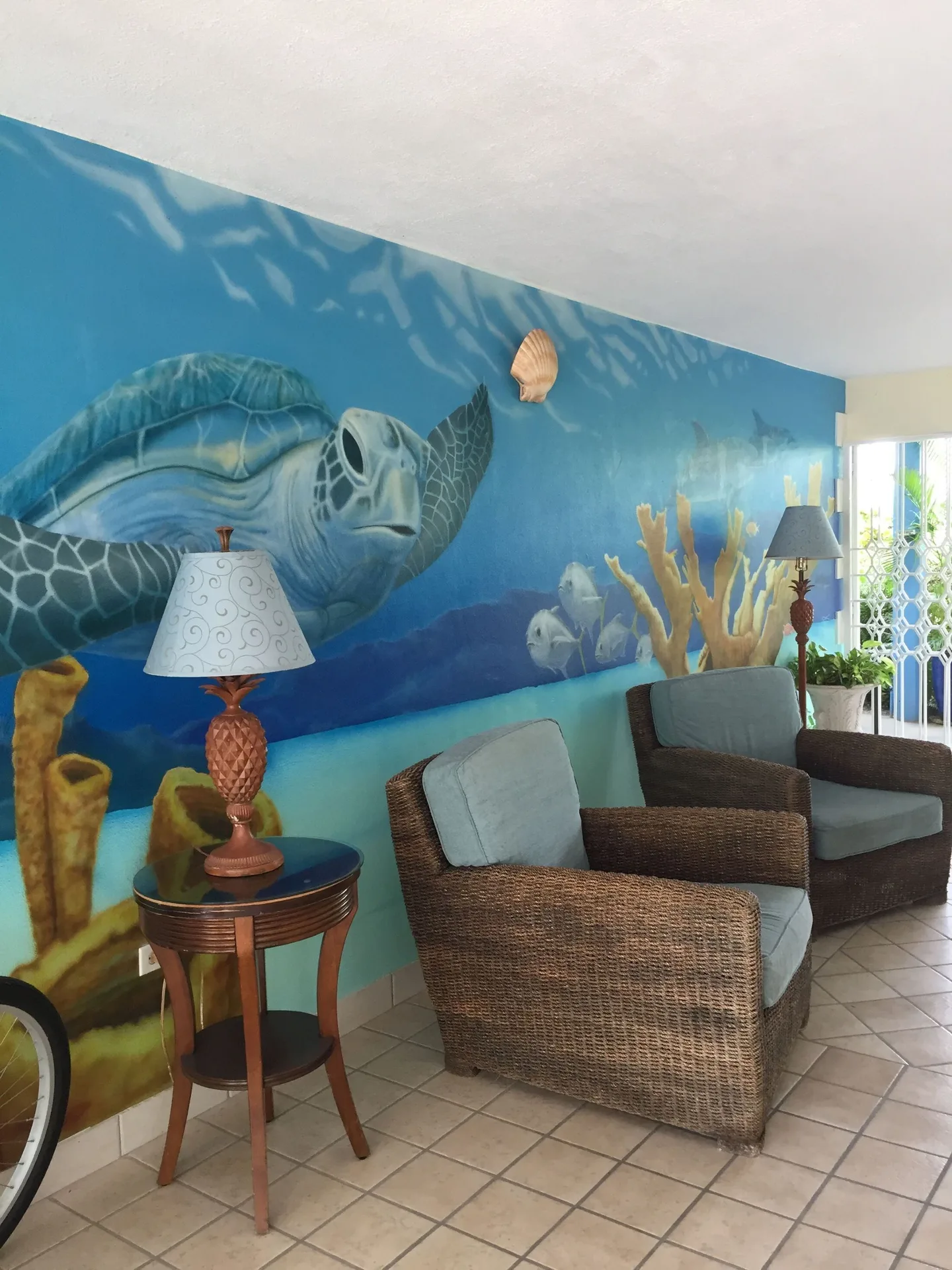 Wicker chairs sit below a sea turtle mural in the lobby at Sibonné Beach Hotel.