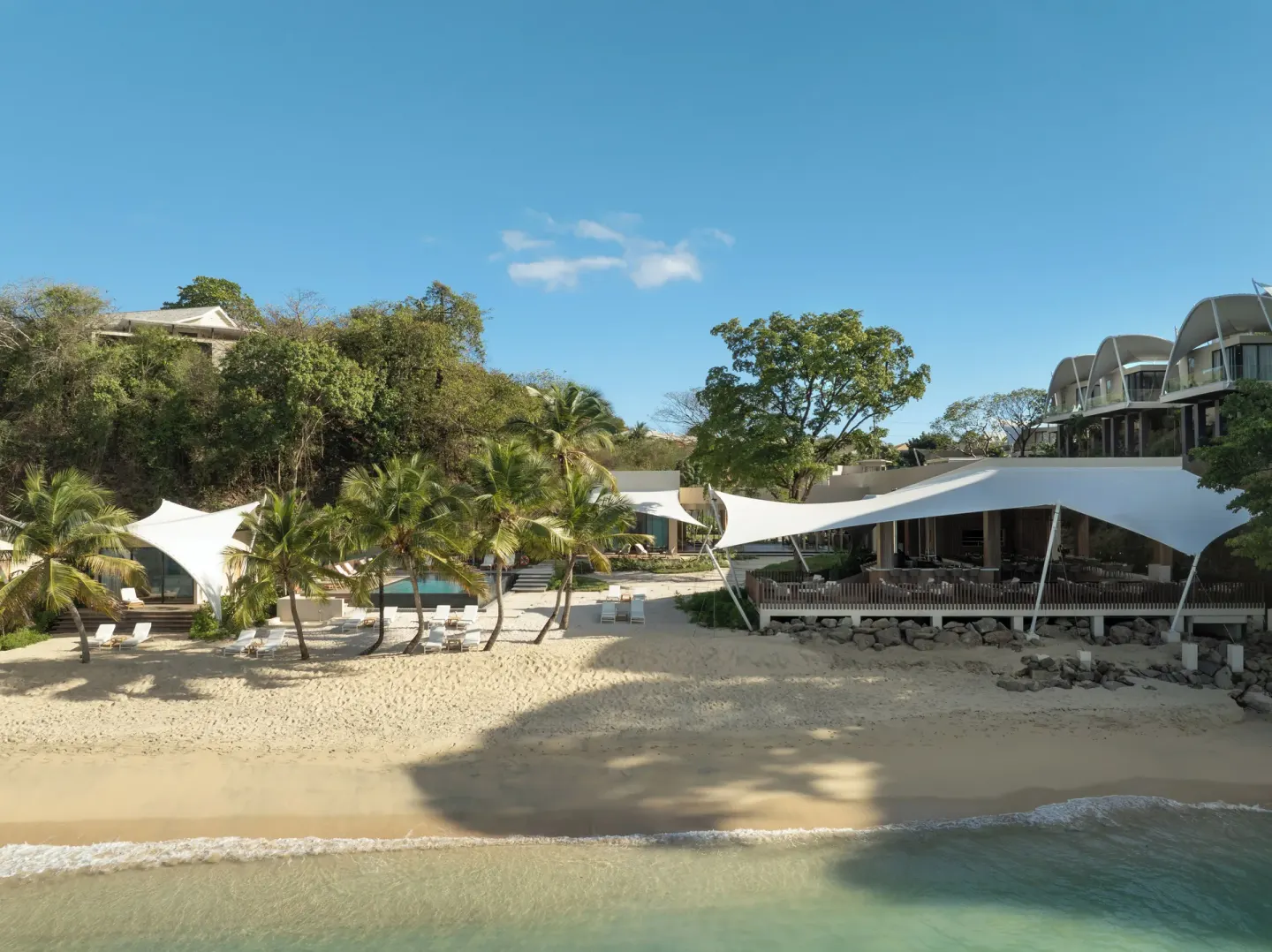 Beach, palms, pool, and waterfront buildings at Silversands Beach House Grenada.