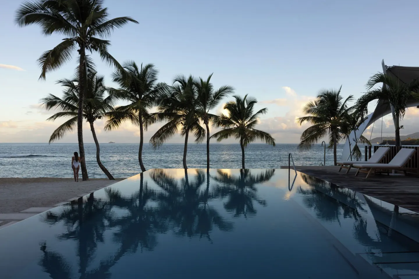 Oceanfront pool with palm trees and loungers at Silversands Beach House Grenada.