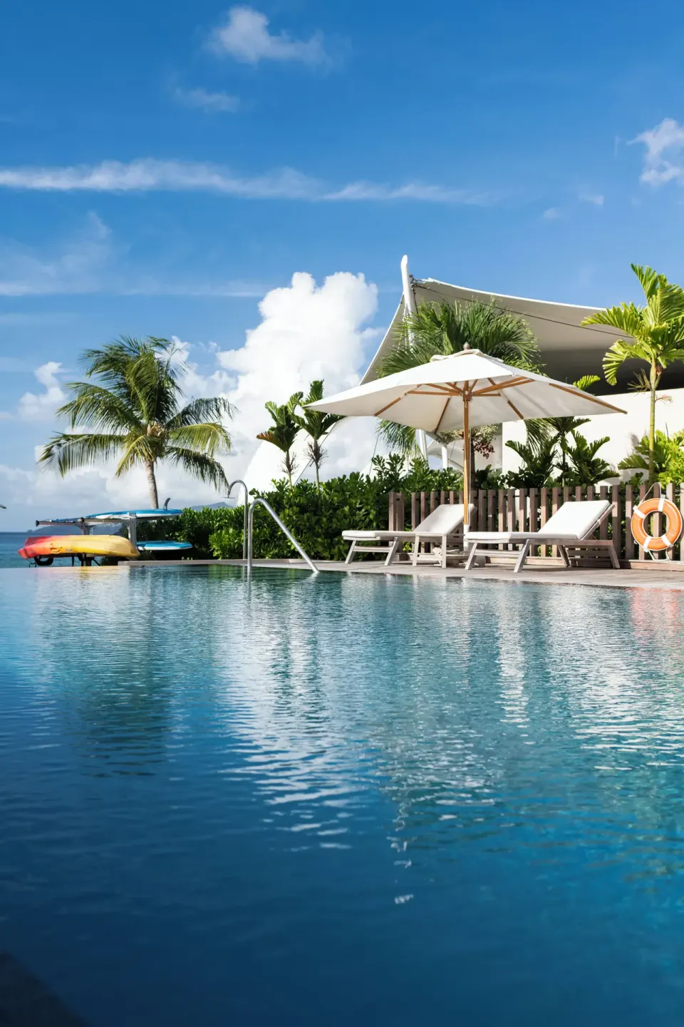 Pool deck with white umbrellas and loungers at Silversands Beach House Grenada.