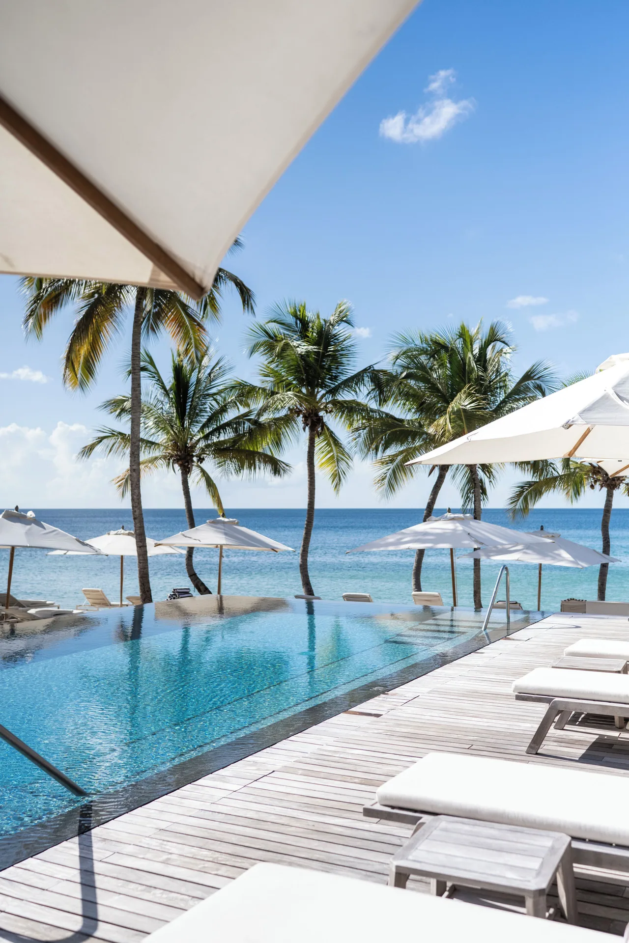 Poolside loungers and beach umbrellas by the sea at Silversands Beach House Grenada.
