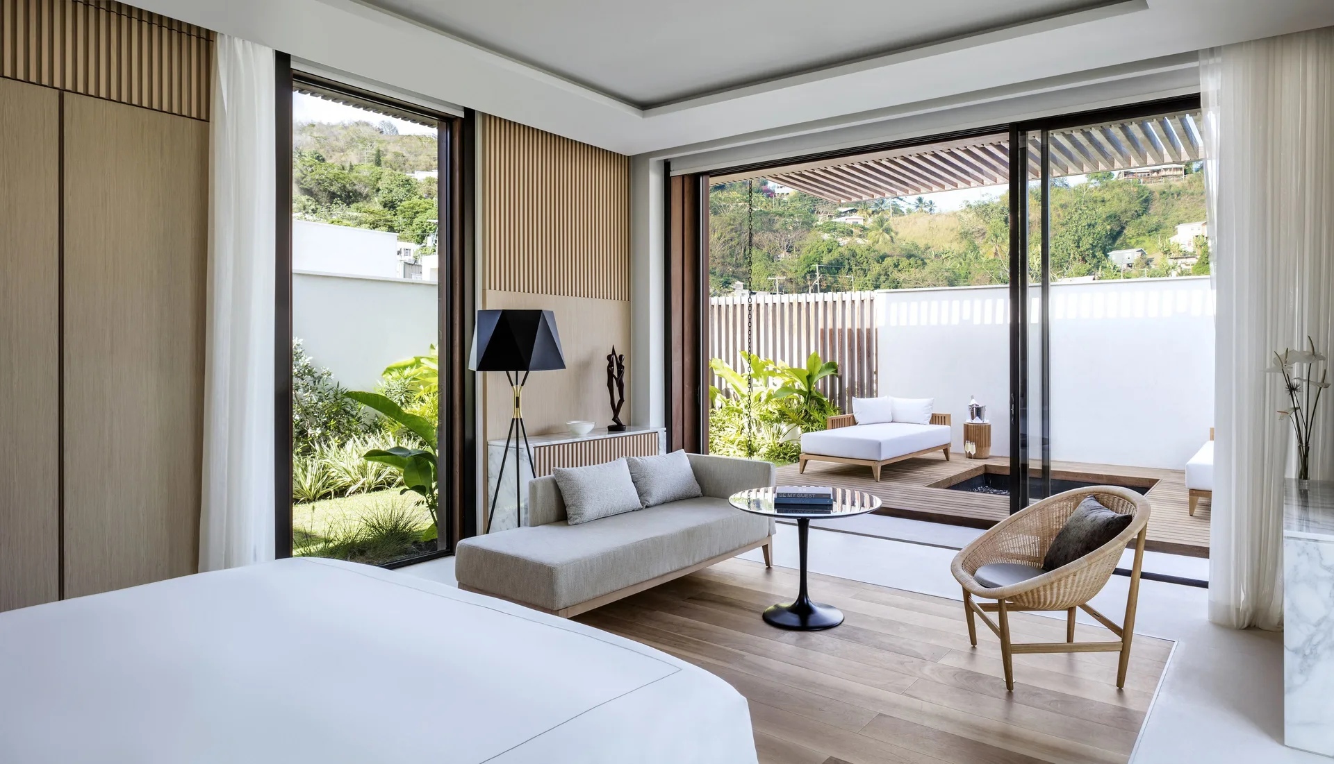Bedroom with bed, lounge seating and patio doors at Silversands Beach House Grenada.