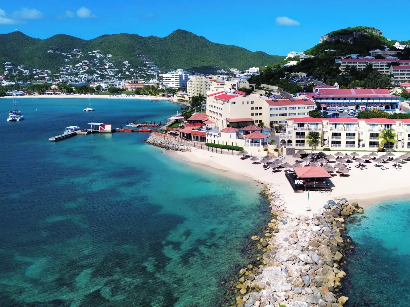 Aerial beachfront view of Simpson Bay Resort, Marina & Spa with hills in the background.