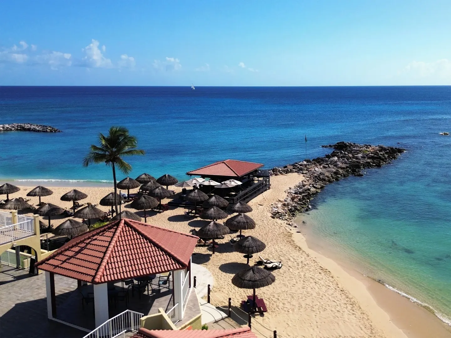 Beach palapas and a rocky breakwater at Simpson Bay Resort, Marina & Spa.