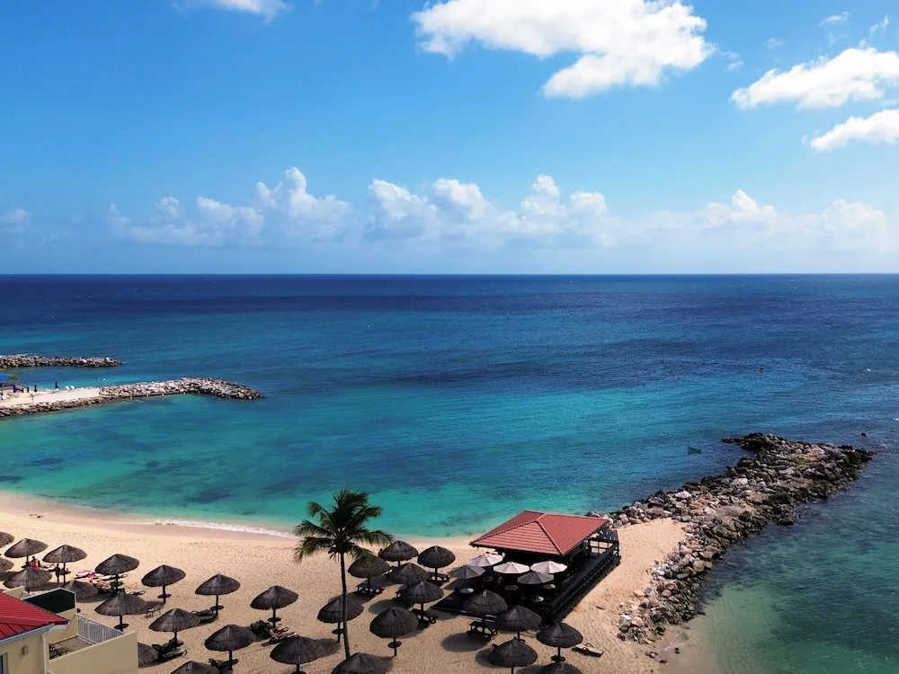Beach umbrellas, palm tree, and ocean view at Simpson Bay Resort, Marina & Spa.
