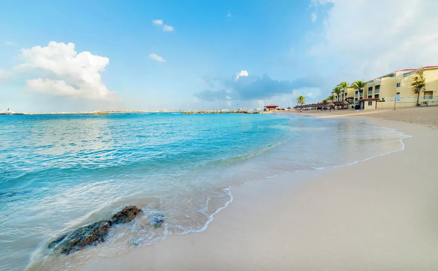 Beachfront and turquoise water at Simpson Bay Resort, Marina & Spa with resort buildings along the sand.